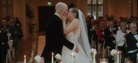 Bride and groom share a romantic wedding kiss before guests at Mitton Hall.