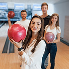 Smiling woman holding a pink bowling ball at King’s Entertainment