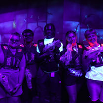Group posing with laser tag vests inside The Fun Lab’s blacklight arena in Blaine.