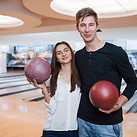 Teen boy and girl smiling with bowling balls in hand