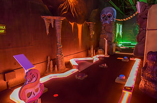 Mini glow golf course with neon lights and themed obstacles at King’s Entertainment