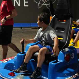 little boy playing bumper cars at the fun lab