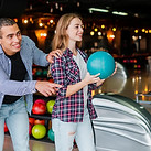 Young girl at bowling alley holding a teal bowling ball