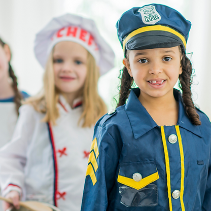 Children dressed in different uniforms smiling towards the camera; career day.