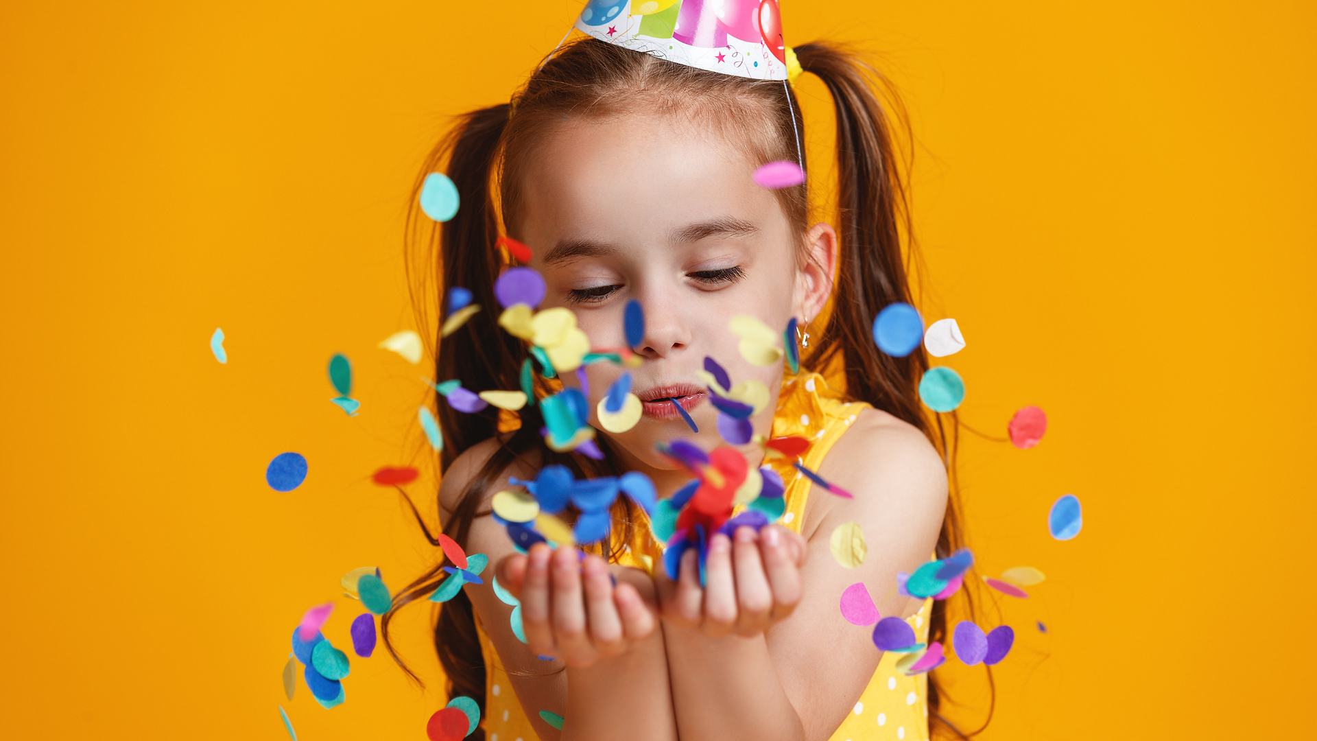 little girl blowing birthday confetti