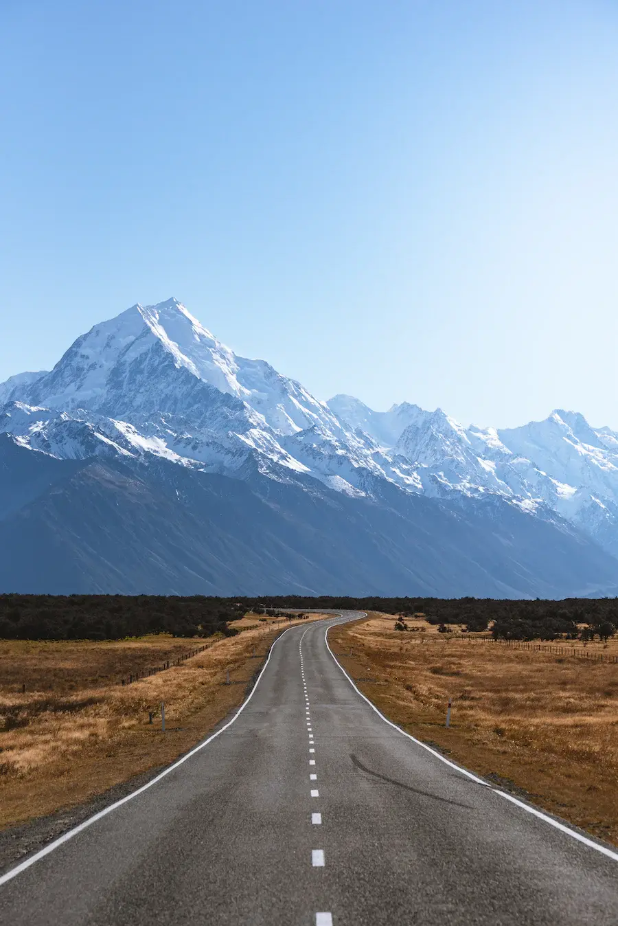 A lone highway leads to a mountain range on the South Island of rural New Zealand