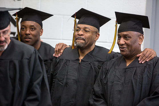 Three students pose in graduation regalia for the Calvin Prison Education Program Commencement
