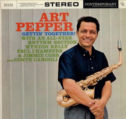 Portada de disco de vinilo de un hombre blanco de pelo negro corto sonriente, con camisa negra , que abrazza un saxofon con el brazo derecho.