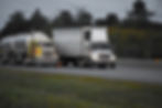 trailer-trucks-driving-road-surrounded-by-beautiful-green-trees.jpg