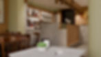 Ampia hall-caffetteria di hotel di montagna con bancone in legno e pietra, tavoli in legno e grande vetrata sul bosco