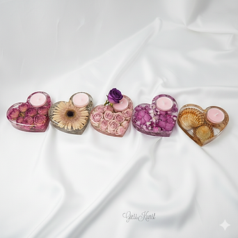 5 Teelichthalter in Herzform.
Das erste besteht aus vielen kleinen dunklen Rosen.
Das zweite aus einer großen Blume.
Das dritte weißt wieder viele kleine Rosen in hellpink auf.
Das vierte ist mit pinken Hortensienblüten gefüllt und das letzte hat größere Herzmuscheln in sich.