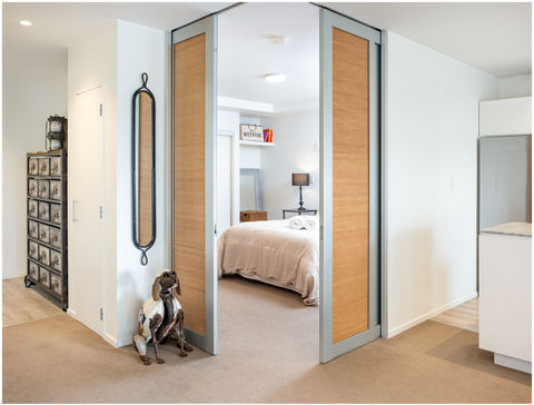 A semi hidden bedroom hides behind retractable doors in an open plan Auckland Airbnb apartment
