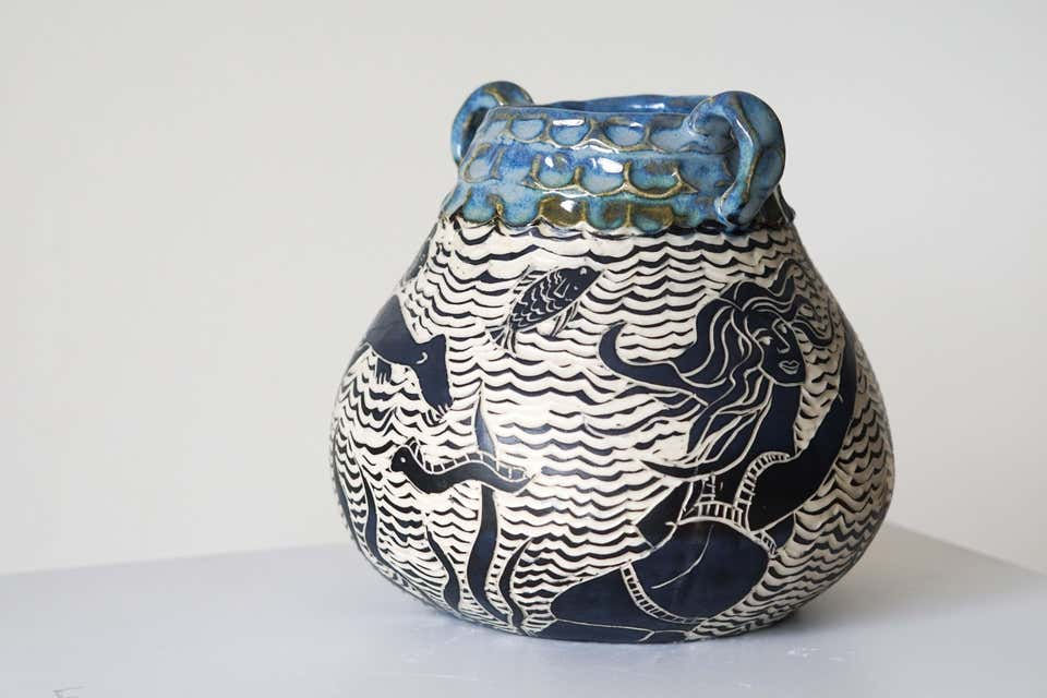 Thumbnail: Detail of the hand-carved clay surface highlighting fine sgraffito linework, fluid maritime silhouettes, and a lip glazed