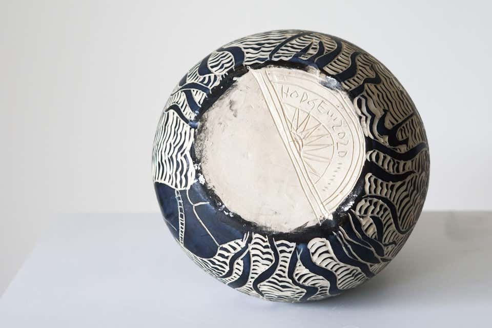 Thumbnail: Detail of the hand-carved clay surface highlighting fine sgraffito linework, fluid maritime silhouettes, and a lip glazed