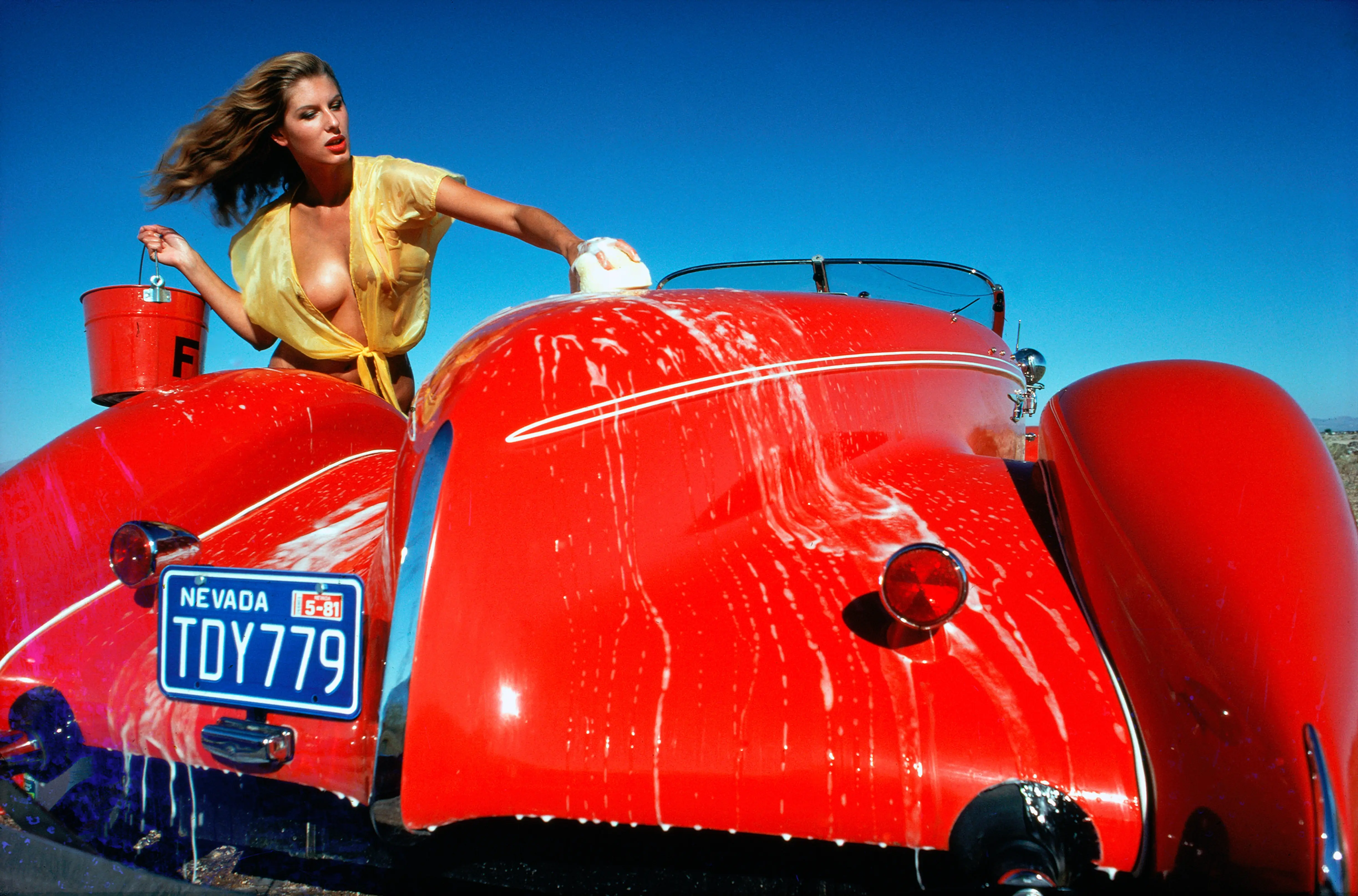Fine art fashion photography print Mintex Calendar 1982 July by Uwe Ommer showing a model washing a classic red sports car