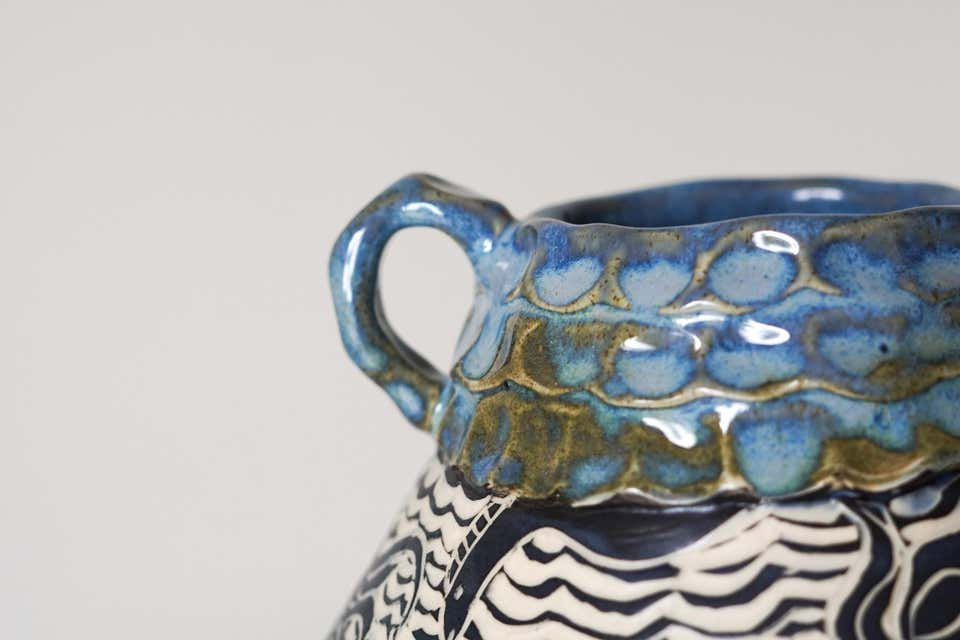 Thumbnail: Detail of the hand-carved clay surface highlighting fine sgraffito linework, fluid maritime silhouettes, and a lip glazed