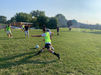 Students playing soccer on a grass field during athletics.