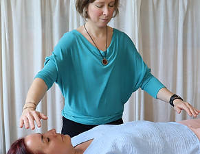 Chakrenbalance mit Klientin, blau gekleidet, Klangenergetik mit Stimmgabeln, Birgit Führer, weißer Vorhang, Massageliege