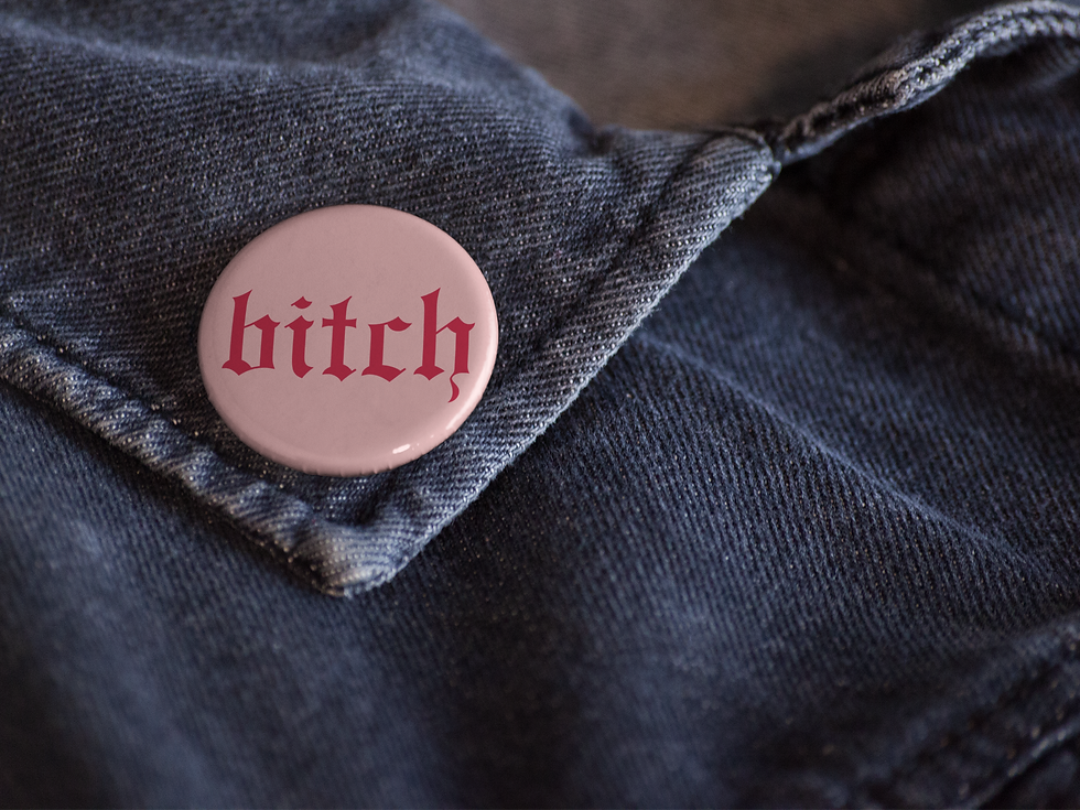 Thumbnail: 1.25-inch pink button, featuring red gothic text that reads 'bitch'. Designed and hand-pressed in house with lots of love.