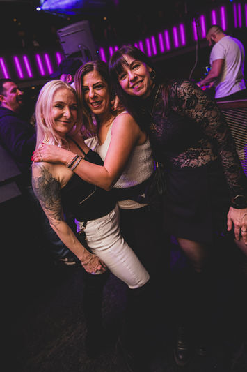 Drei lächelnde Frauen in einem Club.