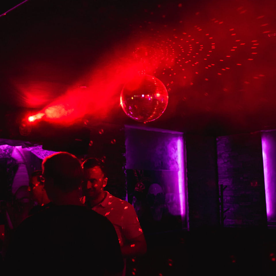 Diskokugel und rote Lichter im Club mit Leuten