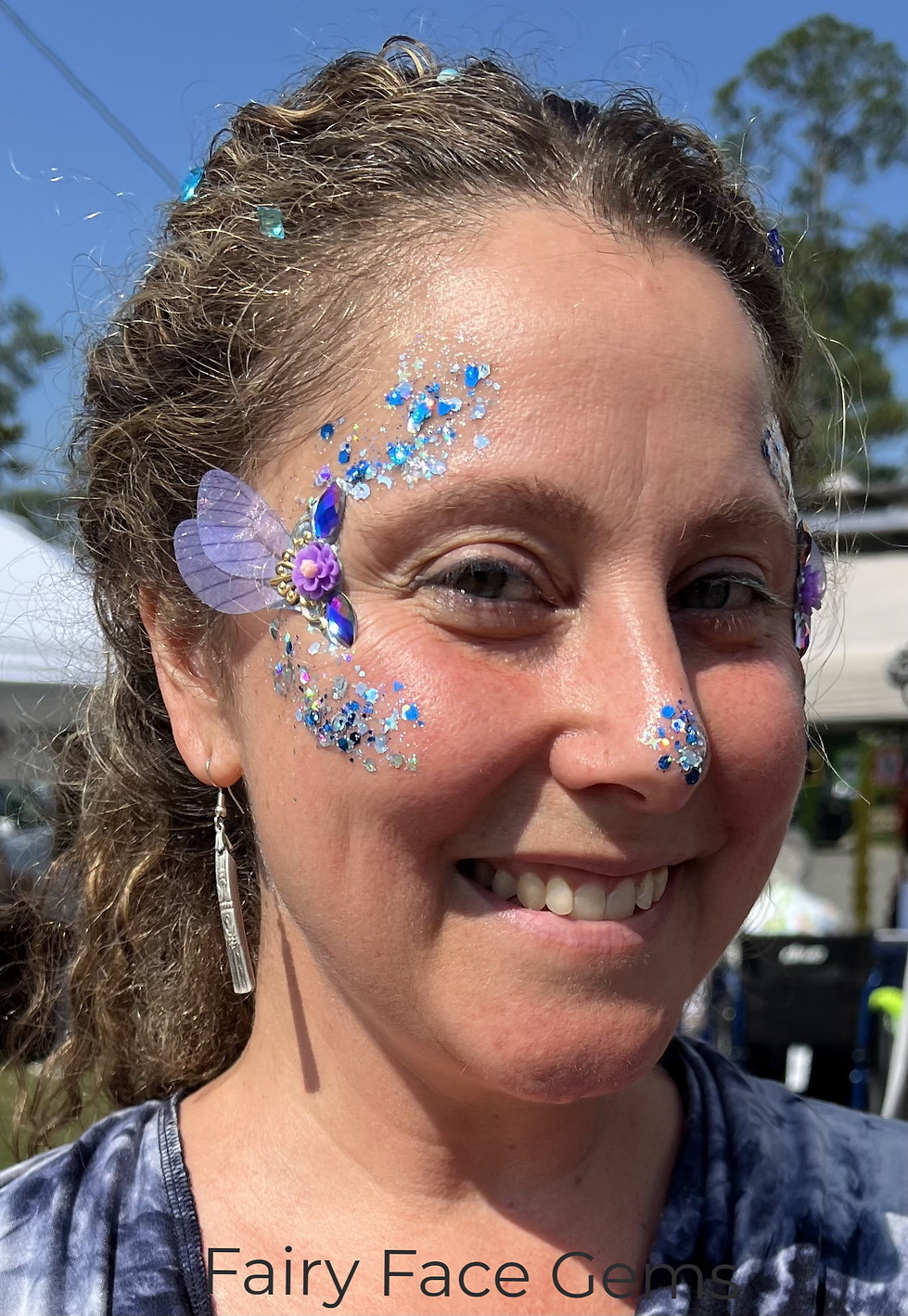 Smiling woman with blue face glitter and butterfly adornments