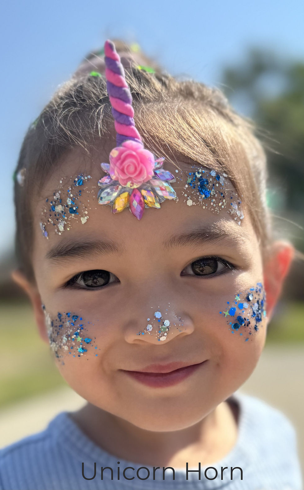 Child with unicorn horn and face glitter