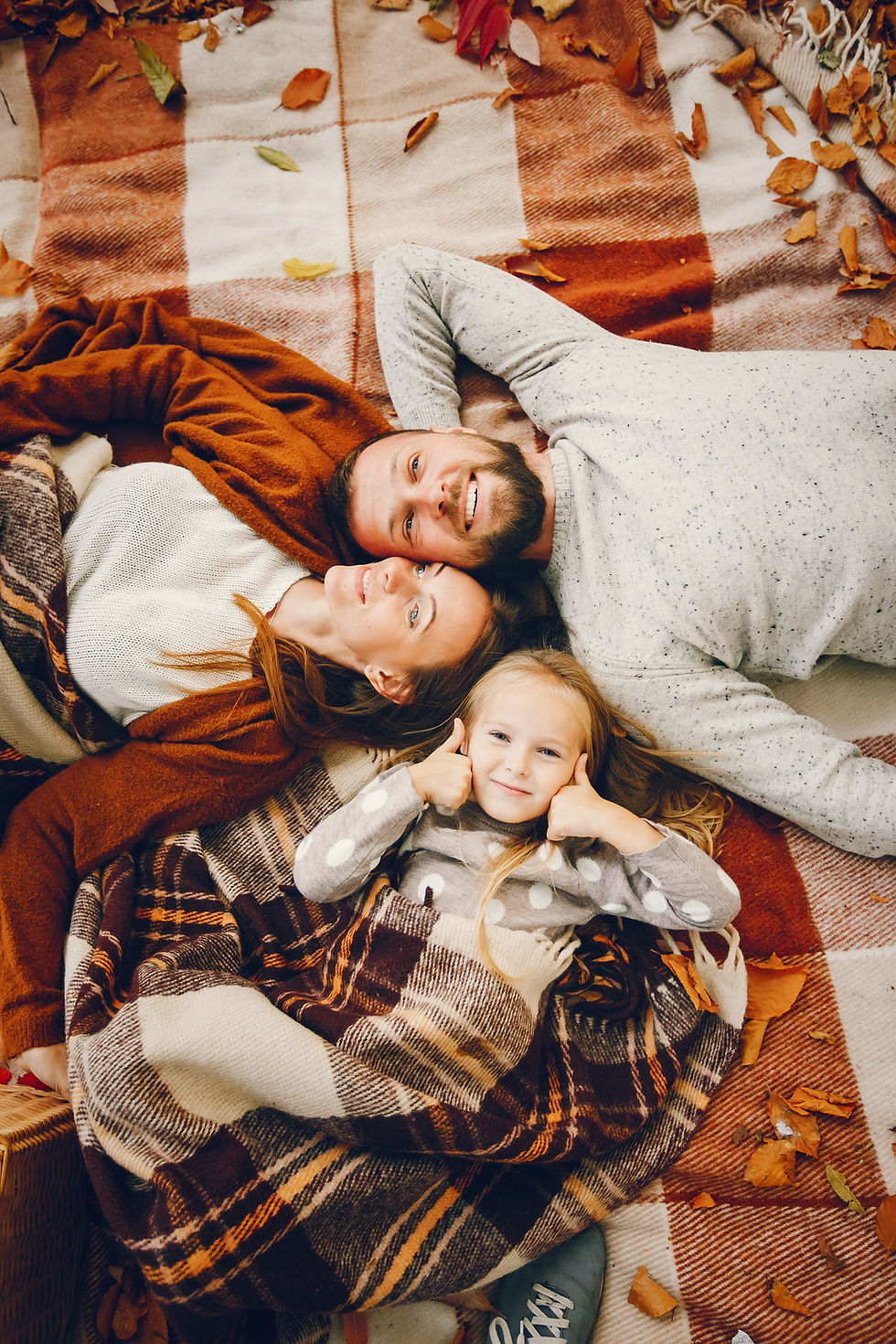 mom dad and little girl on picnic blanket in fall