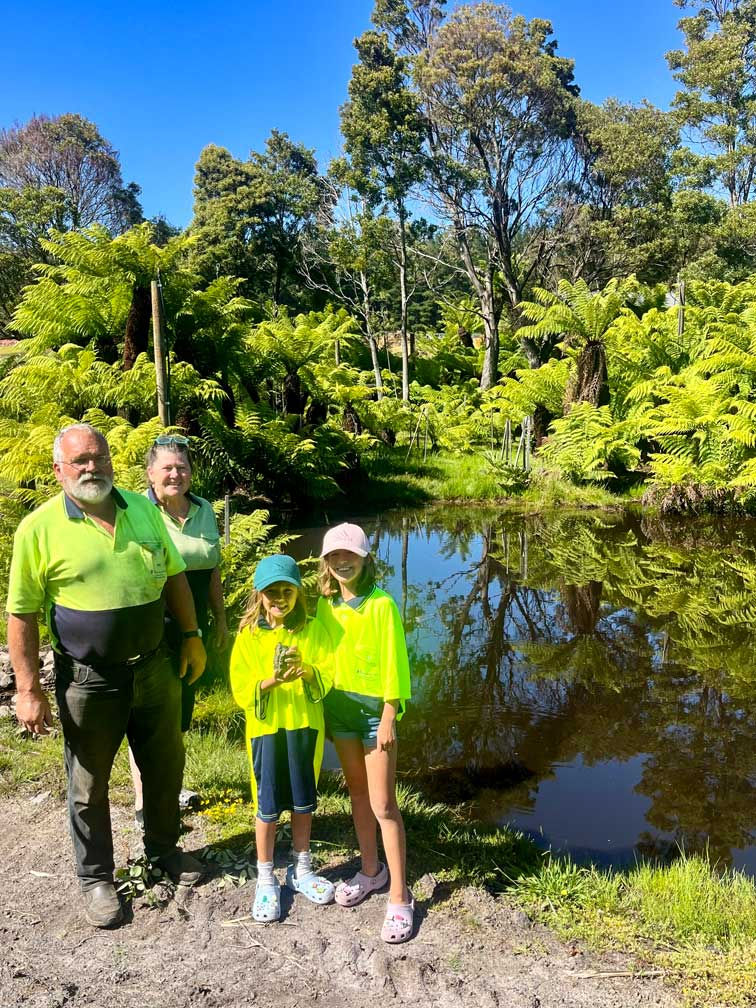 Family standing beside Dicksonia antarctica tree ferns at Fernmania nursery in Tasmania