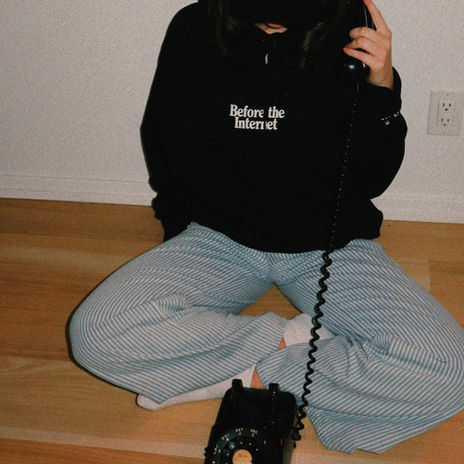 Person in 'Before the Internet' hoodie using a rotary phone