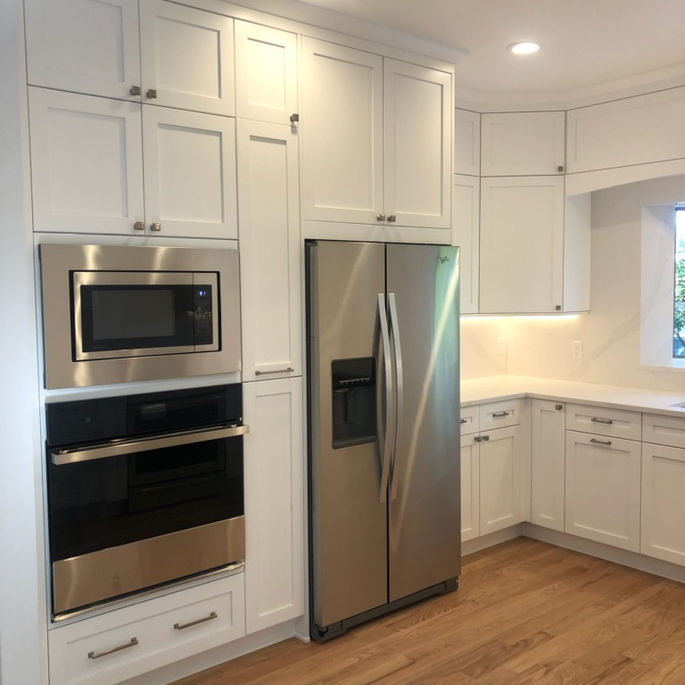 A classic white shaker kitchen remodel with wall ovens and custom valence.
