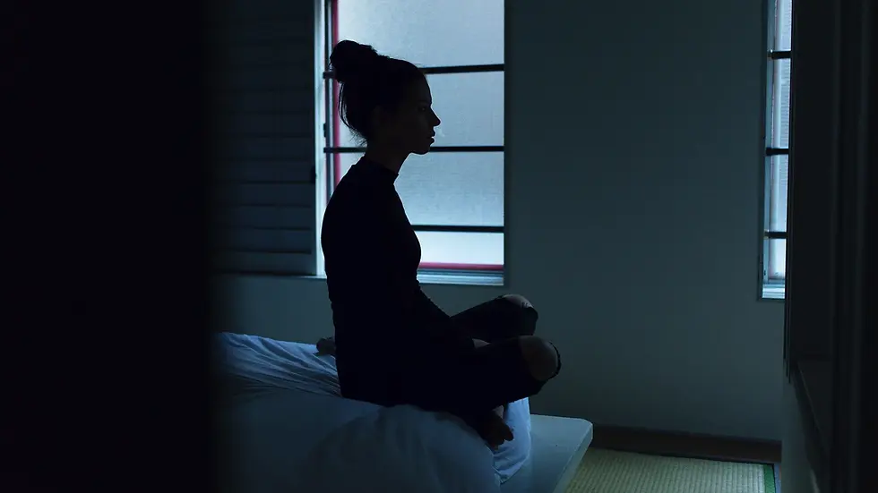 A woman meditating near a window using a wearable headset