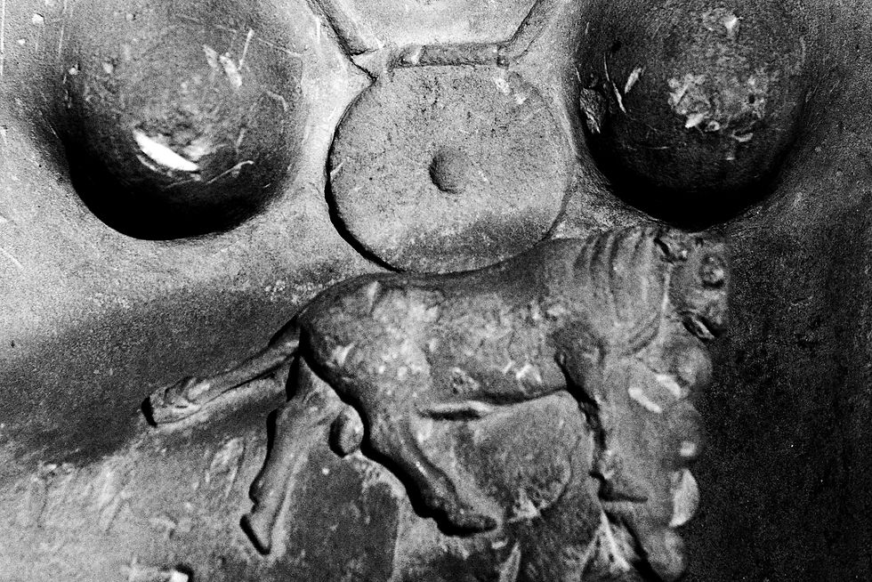 Limestone torso of a woman carrying a bull