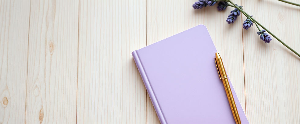 light wood table top with an angled lavender notebook, gold pen_edited.jpg