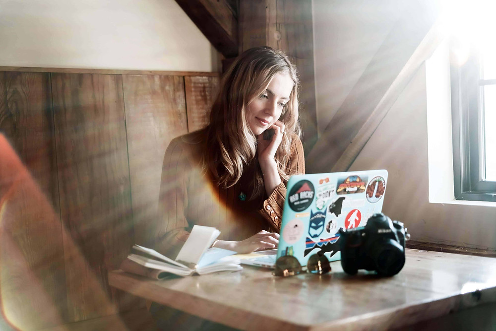 Photographer sitting at a table working on their business on a laptop.