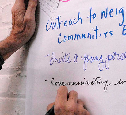 Hands writing notes on ecumenical outreach and community engagement