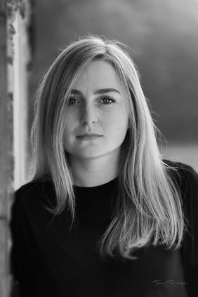 Junge Frau mit blonden Haaren, schaut in die Kamera, schwarz-weiß.