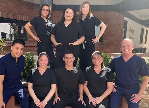 Team of dental professionals posing together outside the office smiling for photo