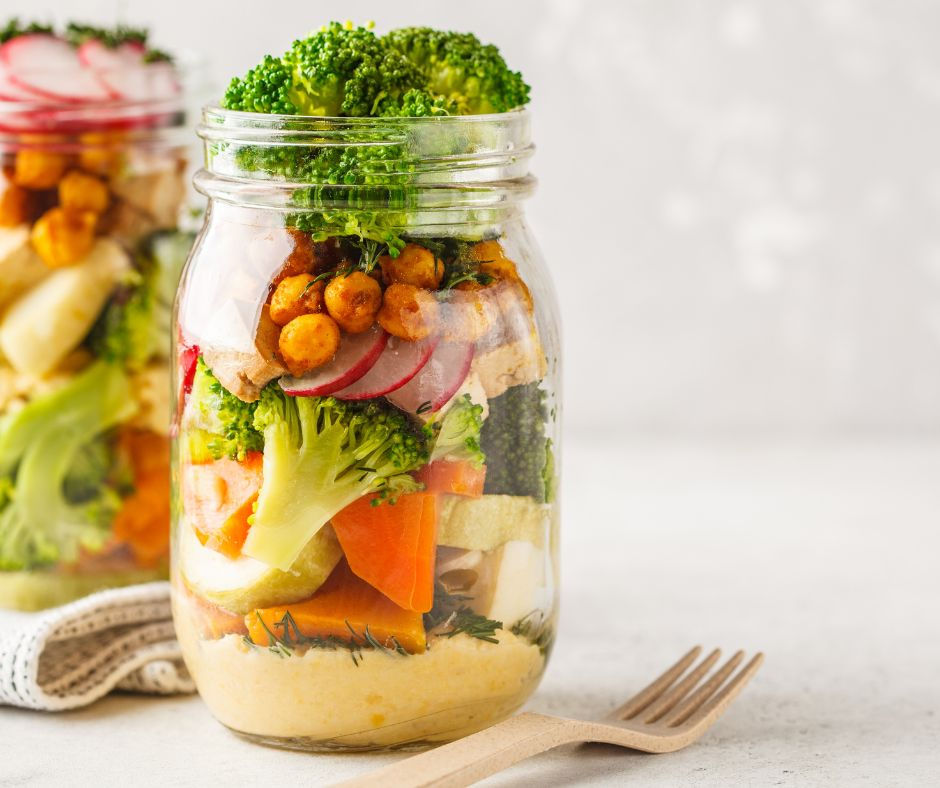 a glass mason jar with salad ingredients layered inside