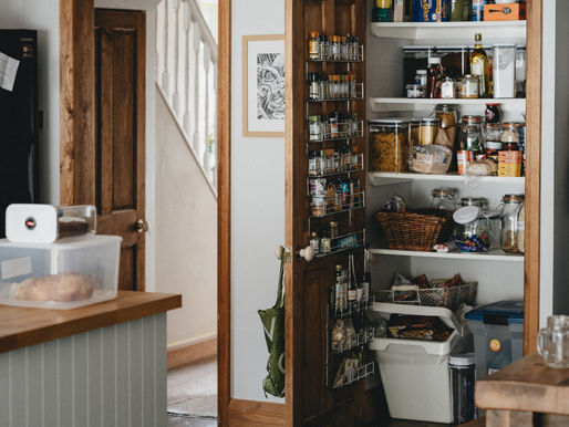 an open door revealing a pantry with jars of spices and foods