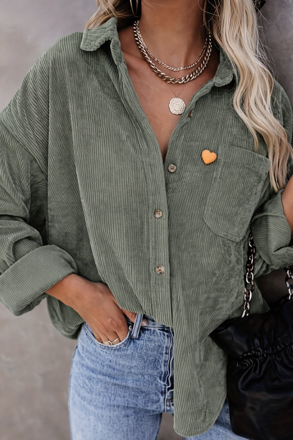 Chemise verte avec pin’s cœur orange sur la poche.