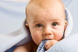 Baby biting warm blanket in cozy house