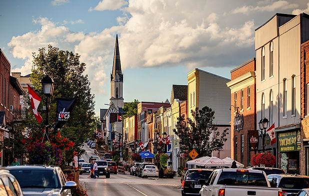 A scenic view of downtown Newmarket, Ontario, featuring historic architecture, vibrant storefronts, and a church steeple. Irving Security Corps provides trusted security services in Newmarket, specializing in residential, commercial, retail and event protection.