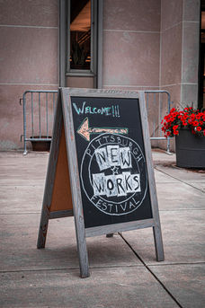 Chalkboard sign that says "Welcome!" and has the Pittsburgh New Works Festival logo.