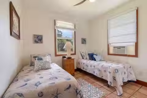 Guest bedroom at Kauai Frog House vacation rental with two beds and a warm, welcoming atmosphere perfect for a shared stay