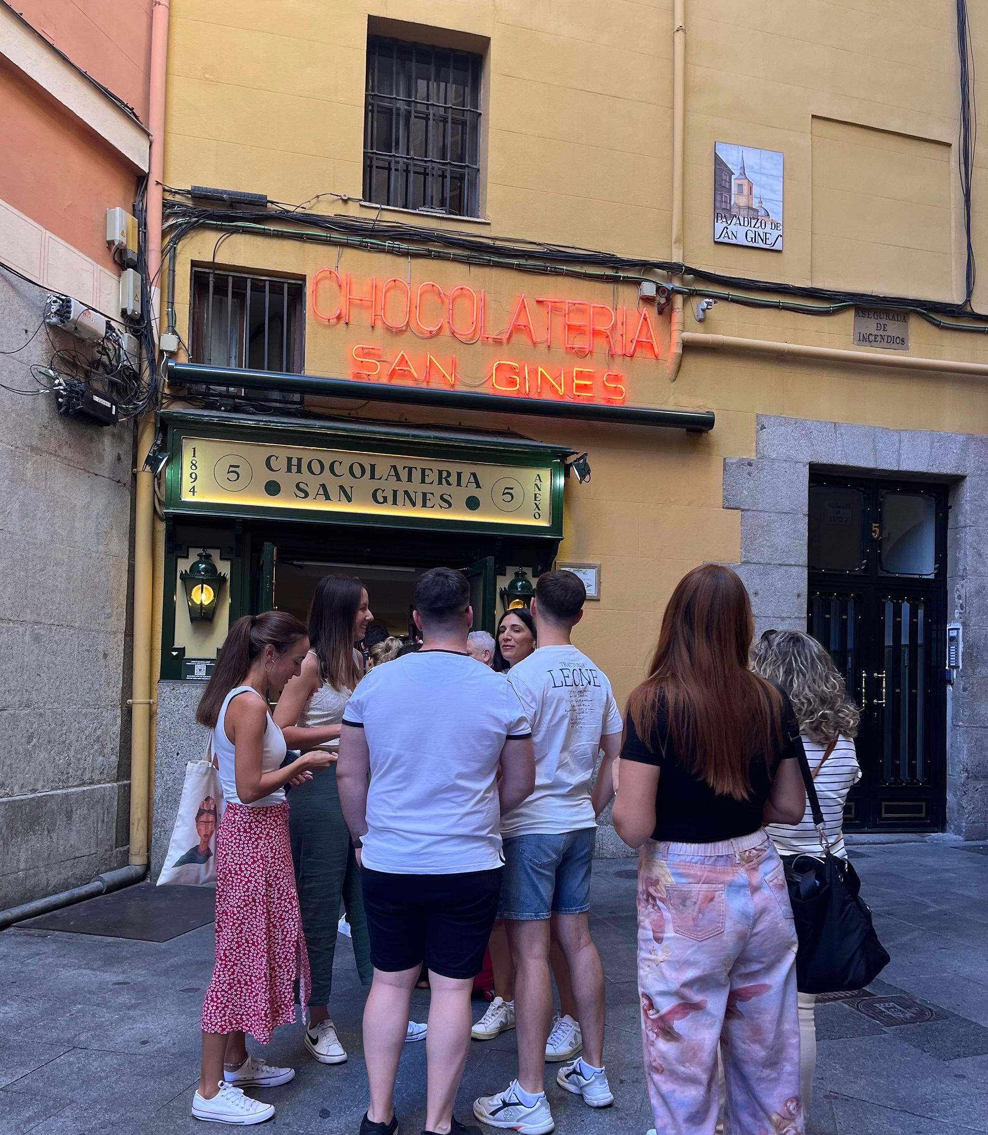 Entrance of Chocolatería San Ginés in Madrid with a line of visitors waiting to enjoy churros and chocolate.