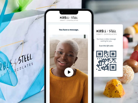 Corporate chocolate gift with a branded QR code card and smartphone displaying a personal VideoGreet message.