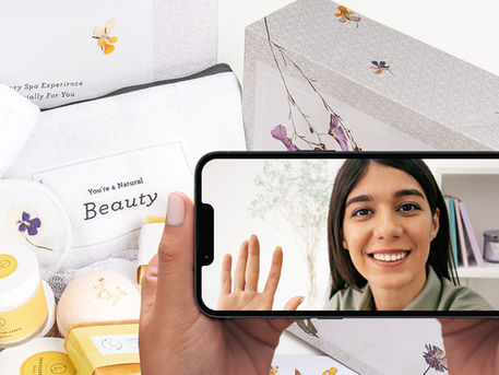 Curated wellness gift box beside a smartphone displaying a personal VideoGreet message.