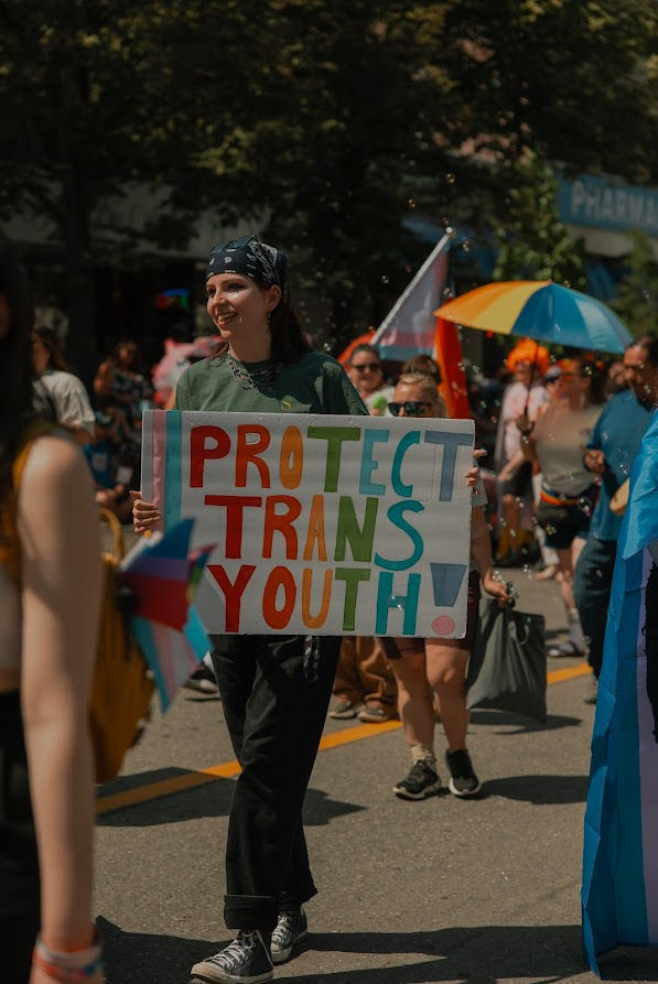people holding a sign while marching in a pride parade.