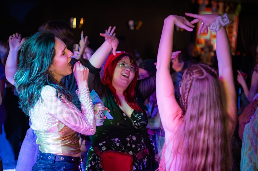 3 people dancing with their arms up in neon light.